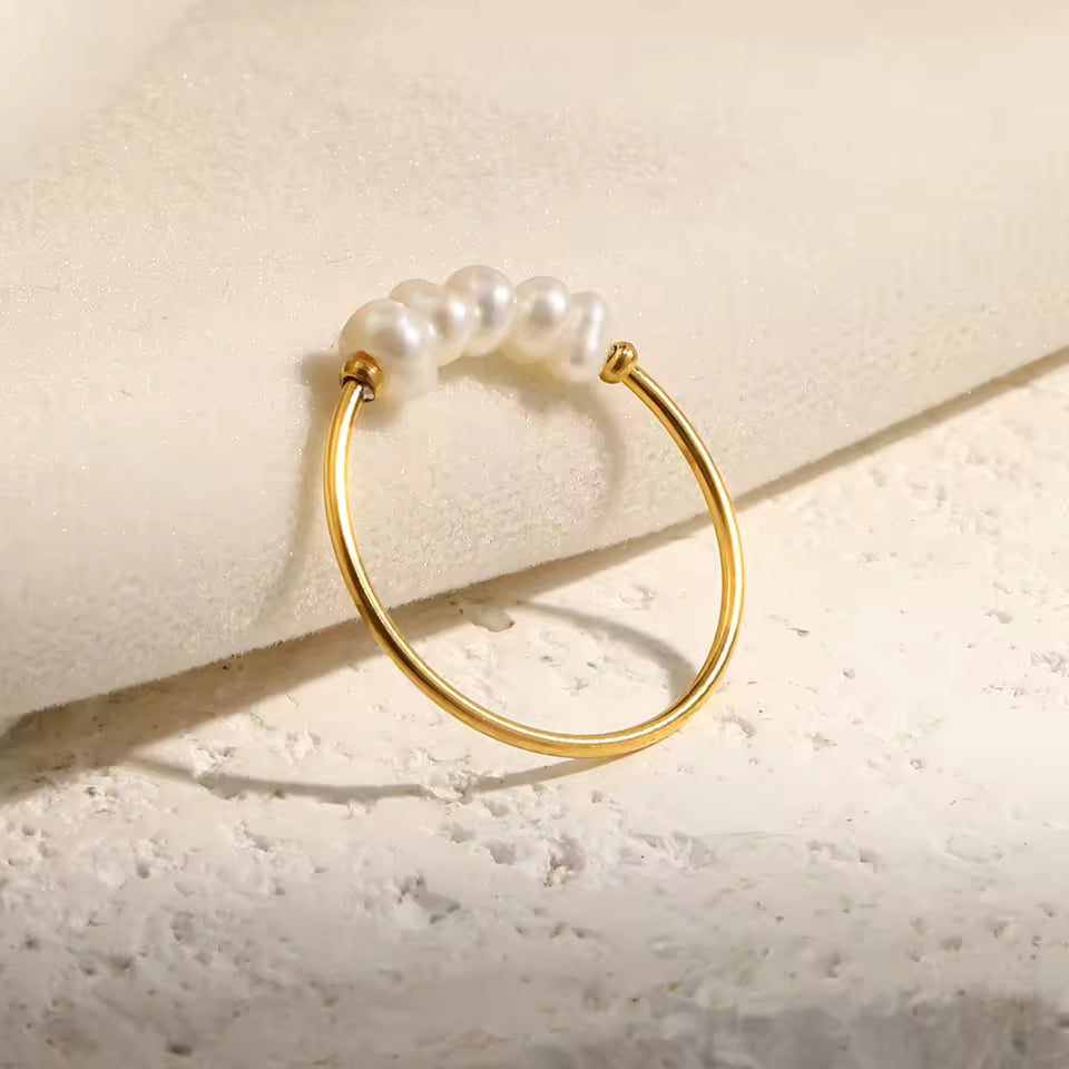 Gold ring with pearls on a textured beige surface