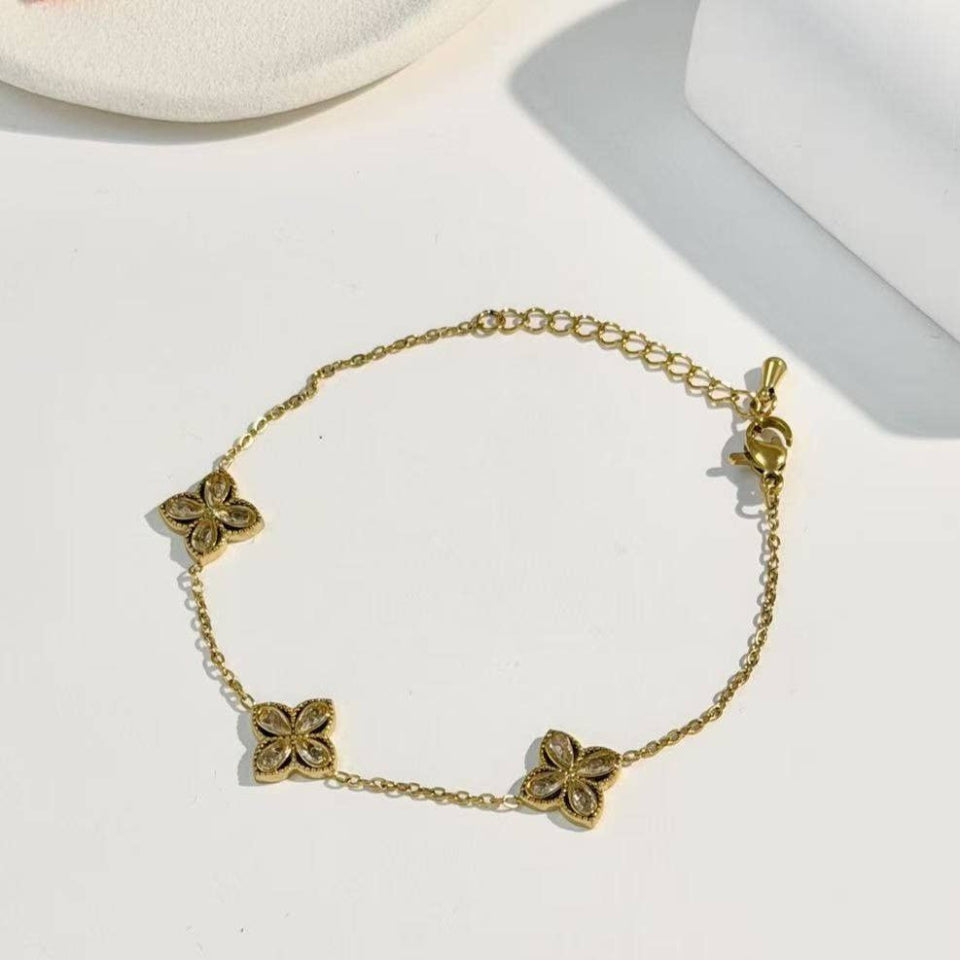Gold bracelet with floral designs on a white surface