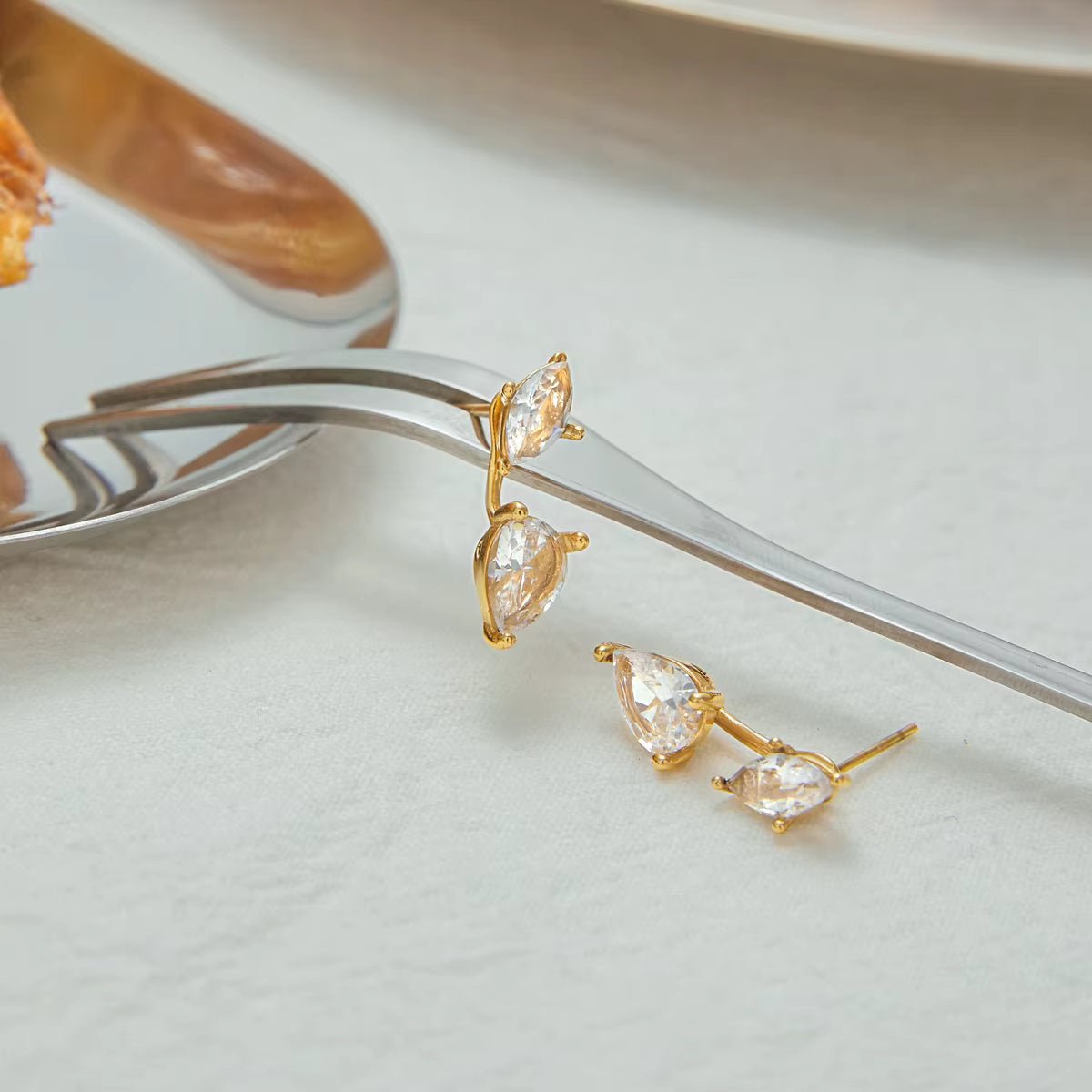Gold earrings with clear stones on a white surface