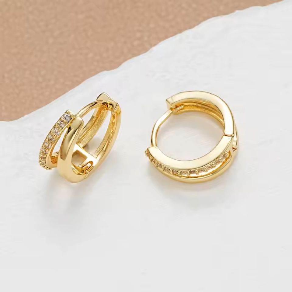 Gold hoop earrings with embedded stones on a light background