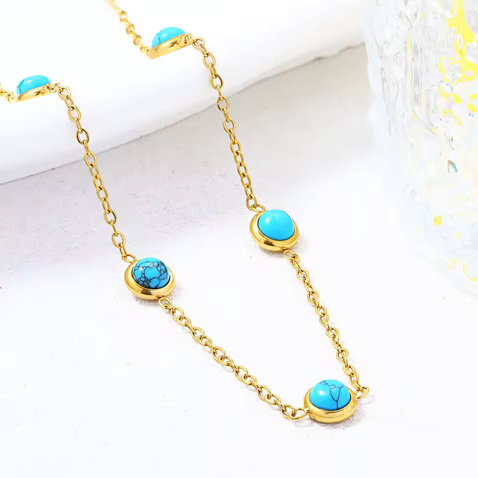 Gold necklace with turquoise stones on a white surface