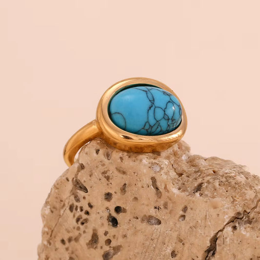 Gold ring with a turquoise stone on a beige rock