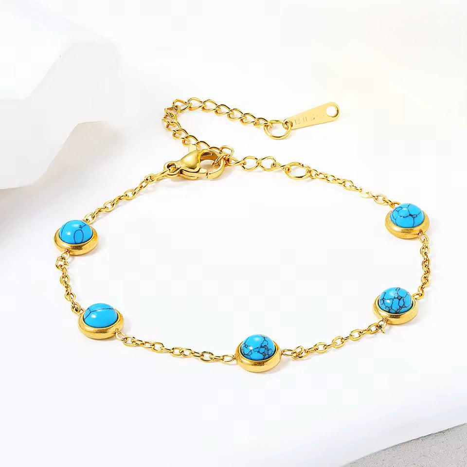 Gold bracelet with turquoise stones on a white background