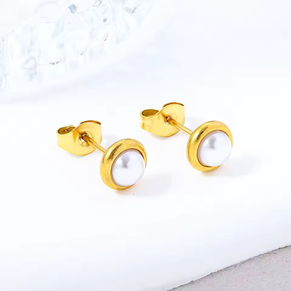 Gold earrings with pearl-like stones on a white background
