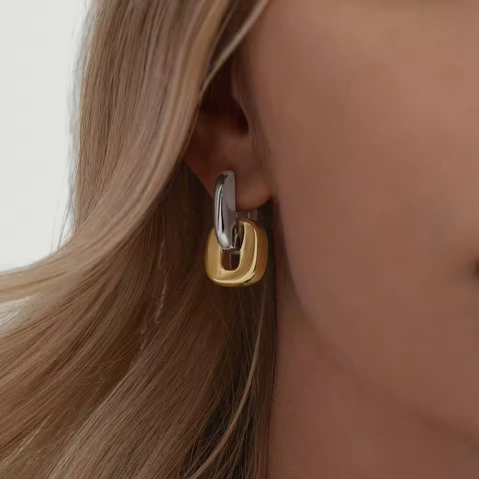 Close-up of a person wearing a gold and silver hoop earring.