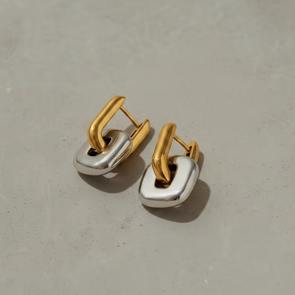 Pair of gold and silver hoop earrings on a gray background