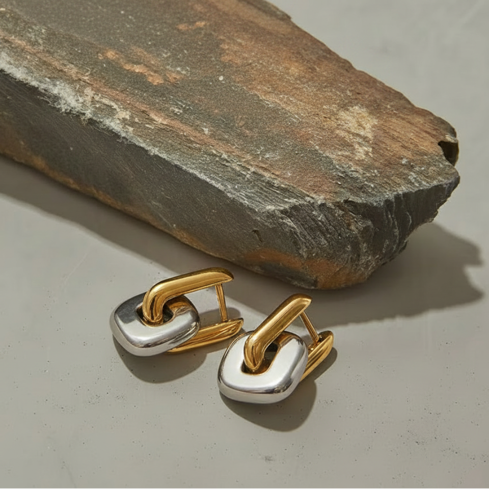 Gold and silver earrings on a stone surface