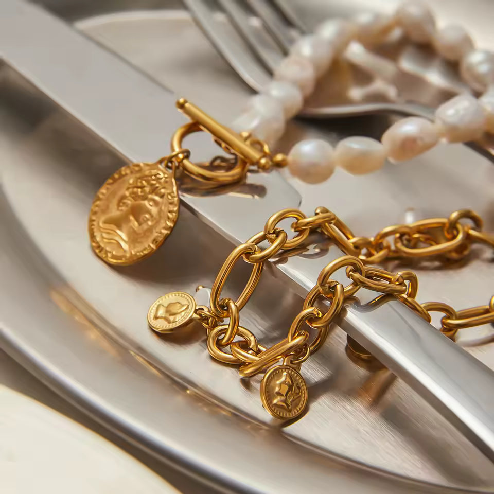 Gold chain bracelet with charms on a white surface